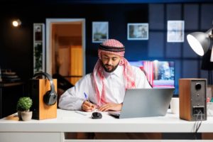 Homme arabe rédige des notes devant son odinateur